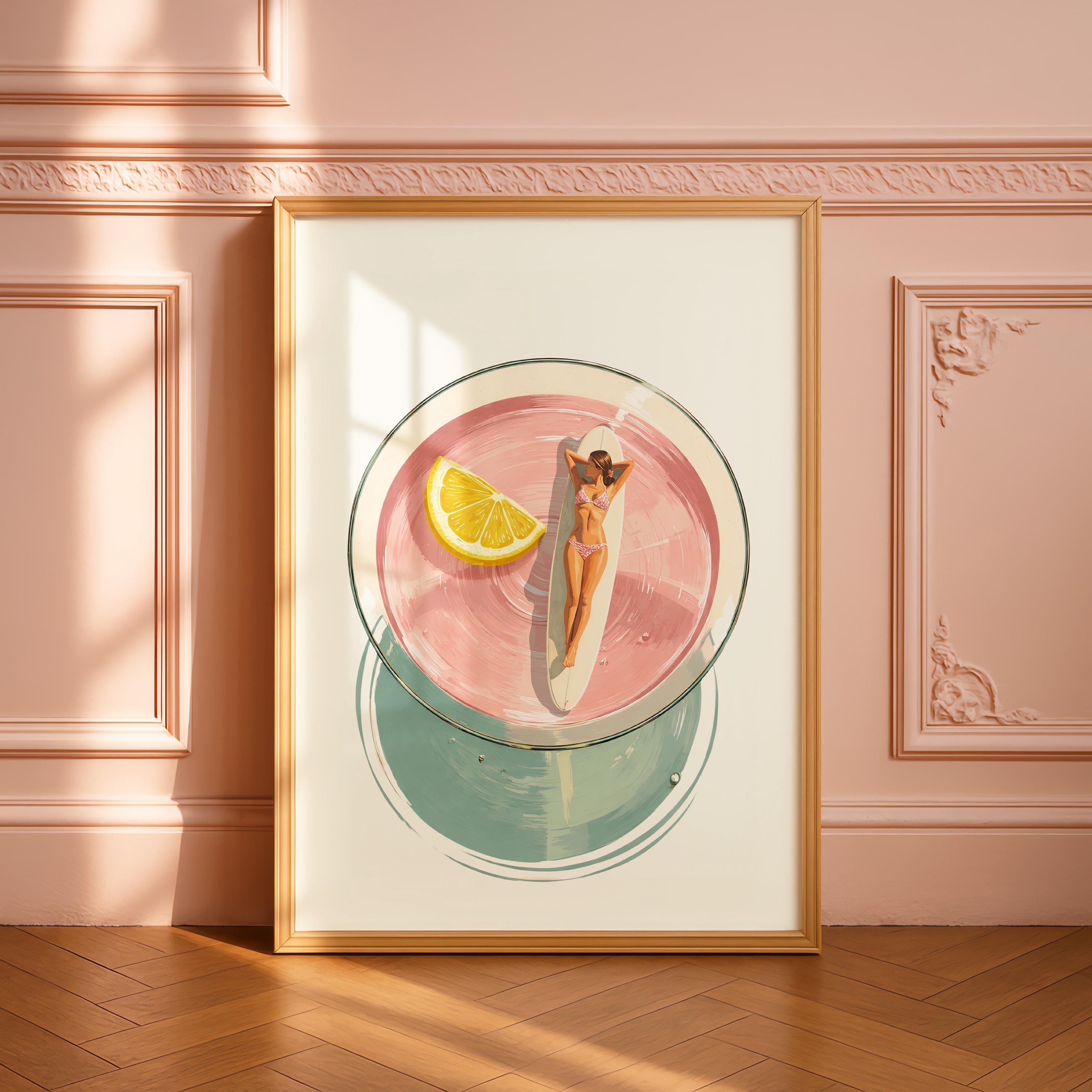 May include: A framed art print depicts a cocktail with a woman sunbathing on a surfboard inside. The drink is pink with a lemon wedge. The bottom of the glass is a teal circle. The frame is gold.